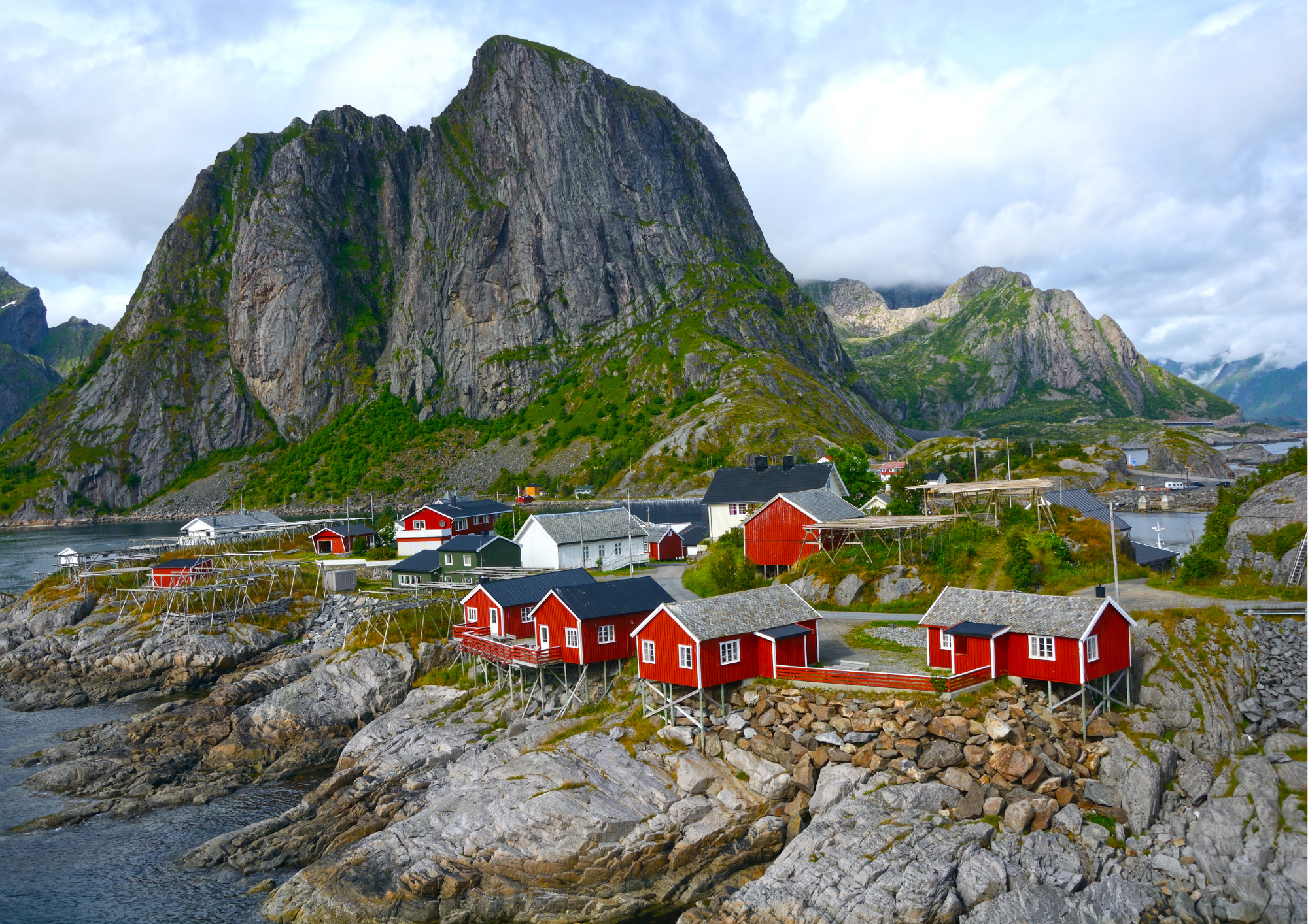 red fishing huts on rocky coast with mountains in Lofoten